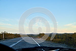 View from car windscreen to highway and tundra in evening time