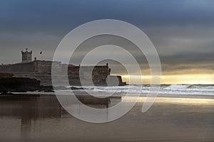 View of the Carcavelos Beach with the Sao Juliao da Barra Fort on the background at sunrise