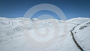 View of cars driving on narrow road in winter passing through snow-capped Dongda Mountains,Tibet,