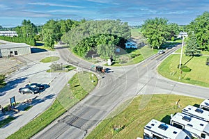 View of cars and RV park in a rural area surrounded by trees