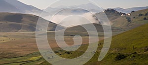 View of Castelluccio di Norcia Umbria at dawn, with mist, big meadows and totally empty blue sky