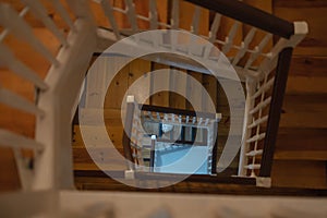 The view of the cat in the perspective of a wooden staircase, the view inside the house from top to bottom.