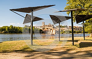 View of the cathedral with the mills and the Duero river where there is a barge crossing the water with tourists during a sunny su