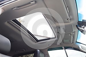 View of the ceiling of the car with a transparent glass hatch for airing, opening in summer while driving fast in the gray cabin