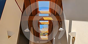 View of ceiling of gable roof without attic with three plastic windows,finished of clapboard,white lamps.Selective focus