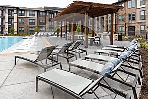 View on the chaise lounge chairs, swimming pool and rooftop dining area in modern residential