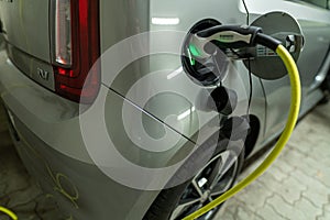 View at a charging electric car by a pluged in type 2 charging wire, green light is glowing as sysmbol for the active