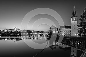 View on Charles Bridge and Prague Castle over Vltava River during early night with wonderful blue sky and yellow city