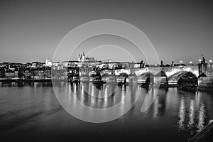 View on Charles Bridge and Prague Castle over Vltava River during early night with wonderful blue sky and yellow city
