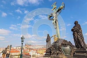 View of Charles Bridge statues and crucifix, Prague Castle in Prague, Czech Republic. Nice sunny summer day with blue sky and clou