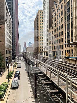 View of Chicago Loop on Wabash Ave, where el tracks cast patterns onto street below, and clouds cover the sky while train