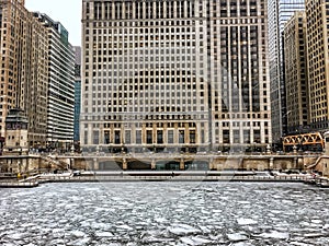 View Chicago riverwalk across a frozen Chicago River and snowflakes during heavy morning snowfall.