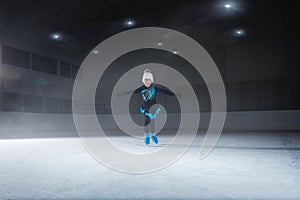 View of child  figure skater on dark ice arena