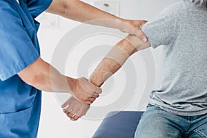 View of chiropractor manipulating with patient arm in massage cabinet at clinic