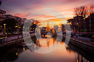 View of the Christmas Tree on a bridge at sunset, with orange clouds. Long exposure picture in Riccione, Emilia Romagna, Italy