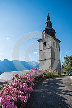 View of church steeple and flowers in the medieval village of Conflans