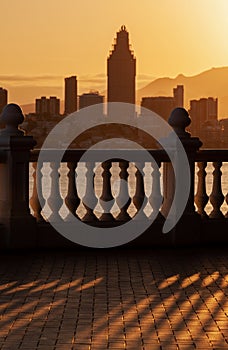 View of the city of Benidorm in the setting sun, sunset, selective focus on the shadow of the balustrade in the foreground