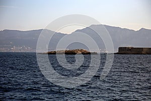 View of the city in the distance over the rocks outcropping from the sea, in the foreground, Parc National des Calanques, Marseill