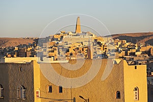 View of city with mud-brick dwelling and tall minaret against clear sky, Algeria, Ghardaia