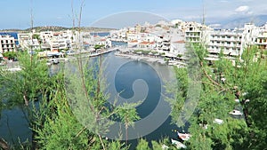 View at the Cityscape of Agios Nikolaos Crete Greece. Boats at small volcano lake voulismeni and its harbor. Traditional houses