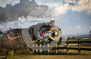 View of a Classic Steam Passenger Train Approaching, With American Flags Attached to a Fence