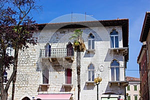 View of a classical colorful croatian house with some palmtrees at the foreground, in the old town of Porec also called Parenzo