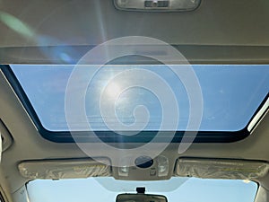 View of the clear sky through the open sunroof hatch of a car on a sunny day