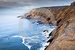 View of a cliff over a coastline with a beautiful misty sea from a view point on a beach in Mossel Bay, Cape Town