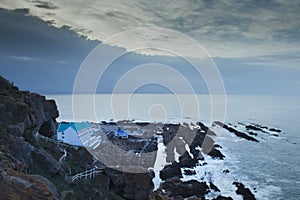 View of a cliff over a coastline with a beautiful misty sea from a view point on a beach in Mossel Bay, Cape Town photo