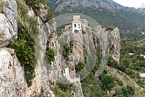 View of the cliffs and the entrance to the town of Guadalest and old bell tower on top of the rock in the province of Alicante,