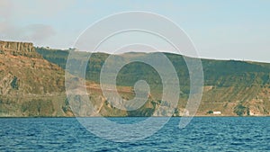 View of cliffy shore of Gran Canaria from floating yacht saling in ocean