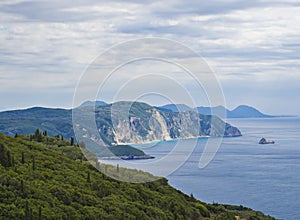 View on cllifs, forest and green hill and turquoise blue sea at Paleokastritsa bay, summer cloudy sky, Corfu, Kerkyra