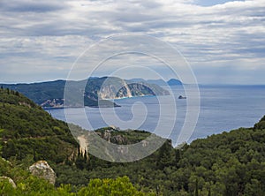 View on cllifs, forest and green hill and turquoise blue sea at Paleokastritsa bay, summer cloudy sky, Corfu, Kerkyra