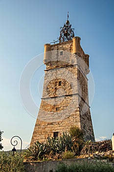 View of the clock tower made of stone on top of the hill with vegetation in Draguignan.