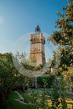 View of the clock tower made of stone on top of the hill with vegetation in Draguignan.