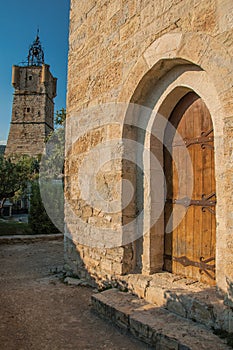 View of the clock tower made of stone on top of the hill and wooden ancient door in Draguignan.