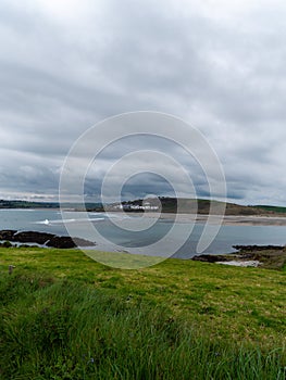 View of Clonakilty Bay on a cloudy day. Thick grass near the sea. The coastline of the south of Ireland. Seaside landscape. Cloudy