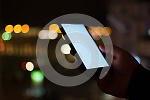 Close-up of person holding mobile phone against illuminated lights at night photo