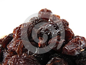From view and close up of a pile of raisins isolated on white background. A raisin is a dried grape.