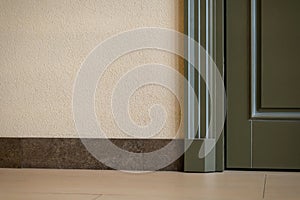 View of a closed door inside an office or cafe. Beige tiles on the floor and granite baseboards along the wall. Evacuation exit