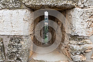 View through the closed loophole in the city`s fortress wall at the city near the Jaffa Gate in old city of Jerusalem, Israel