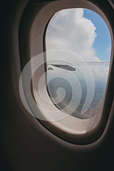 View of clouds and a wing of an airplane seen through from a glass window