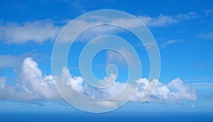 View from the coast of the Easter Island, of blue sky covered by white clouds, over the Pacific Ocean.