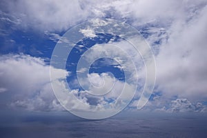 View from the coast of the Easter Island, of blue sky covered by white clouds, over the Pacific Ocean.