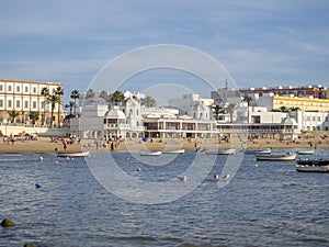 View of the coast of Playa de La Caleta in Spain with sea and boats under the cloudy sky photo