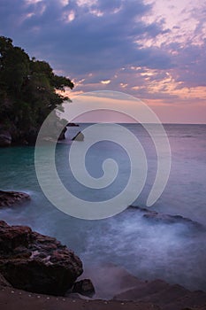 View of coastline on Nosy Komba Island lined with palm trees and boats floating in the sea at sunset, Nosy Komba