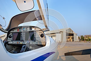 View of the cockpit of a small plane against a hangar.