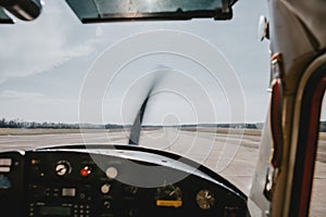 The view from the cockpit of a waiting airplane before take-off on the runway with dashboard and rotating propeller in front
