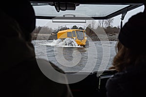 View from a cockpit on a yellow all-terrain vehicle driving through a river