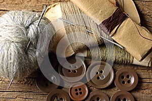 A COLLECTION OF ASSORTED MILITARY REPAIR KIT THREAD AND DARNING YARN AND NEEDLES ON A WOODEN BOARD